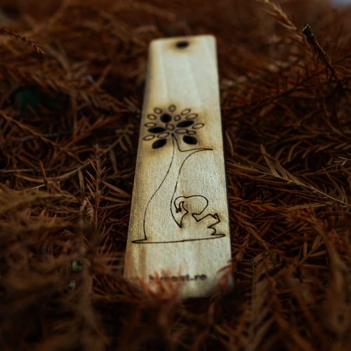 Artistic wooden bookmark on a bed of autumn leaves, featuring intricate engravings.